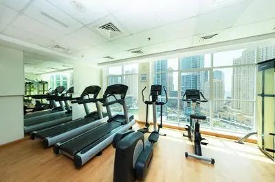 a gym with cardio machines and a large window at 2 Bed in Atlantic Tower 2 by PK Holidays in Dubai