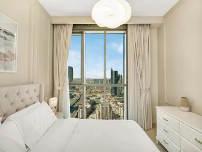 a bedroom with a white bed and a large window at Brand New! Downtown views located on Dubai Mall in Dubai