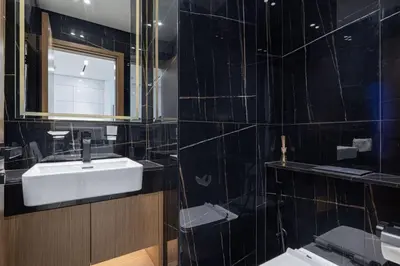 a black tiled bathroom with a sink and a mirror at Large New Apartment Pool in JVC Community in Dubai