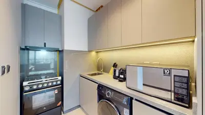 a kitchen with a washing machine and a microwave at Mag Eye 890 - Airy One Bedroom in Meydan in Dubai
