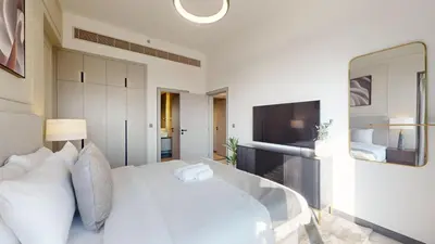 a white bedroom with a large white bed and a television at Mag Eye 910 - Magnificent One Bedroom in Meydan in Dubai