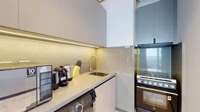a kitchen with white cabinets and a sink and a stove at Mag Eye 910 - Magnificent One Bedroom in Meydan in Dubai
