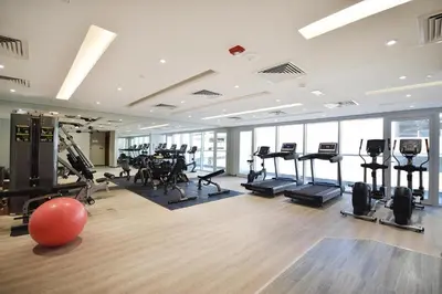 a gym with a lot of treadmills and machines at HAVN - New 1 Bedroom Apartment in Regent Court JVC in Dubai