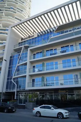 a white car parked in front of a building at HAVN - New 1 Bedroom Apartment in Regent Court JVC in Dubai