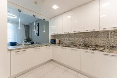 a kitchen with white cabinets and a sink at HAVN - New 1 Bedroom Apartment in Regent Court JVC in Dubai