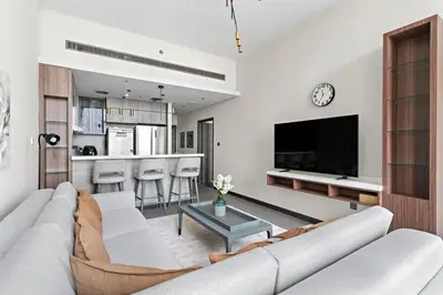 a living room with a large couch and a kitchen at Stonetree - Cozy 1 BR at MBL Near Metro in Dubai