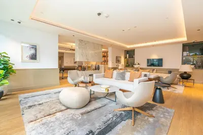 a living room with a white couch and chairs at Sleek & Modern 1BR with Luxury Pool in JVC in Dubai
