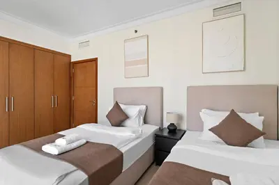 two beds in a bedroom with white walls and brown cabinets at Stonetree - Spacious 2BR at Dubai Creek Residences in Dubai