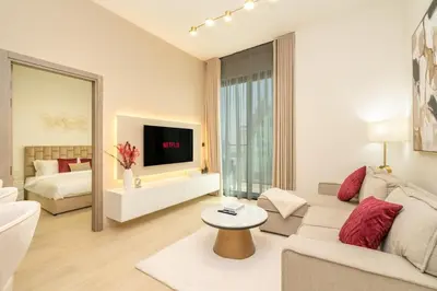 a living room with a couch and a tv at Luxury 1BR Apartment in JVC with Stunning Pool in Dubai