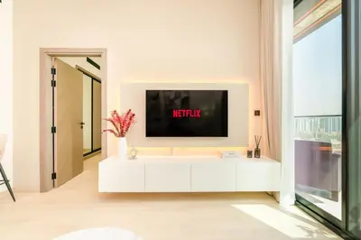 a living room with a tv on a white cabinet at Luxury 1BR Apartment in JVC with Stunning Pool in Dubai