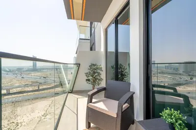 a chair on a balcony with a view of the desert at Luxury 1BR Apartment in JVC with Stunning Pool in Dubai