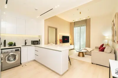 a kitchen and living room with a washer and dryer at Luxury 1BR Apartment in JVC with Stunning Pool in Dubai