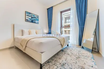 a bedroom with a white bed and blue curtains at Community View 2BR with Balcony, Surf at Creek Beach Building 2, Creek Harbour by Deluxe Holiday Homes in Dubai