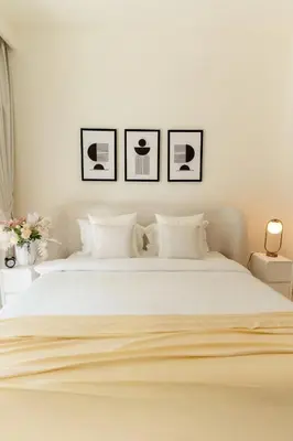 a bedroom with a white bed with three pictures on the wall at 2BD designed by Elie Saab with Private Beach Sea View by EE Holiday Homes in Dubai