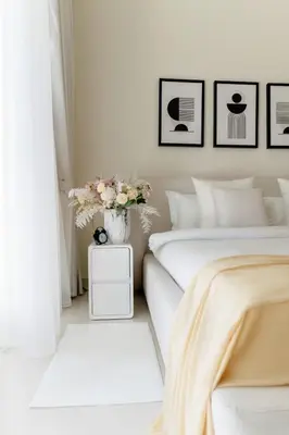 a bedroom with two beds and a vase with flowers on a night stand at 2BD designed by Elie Saab with Private Beach Sea View by EE Holiday Homes in Dubai