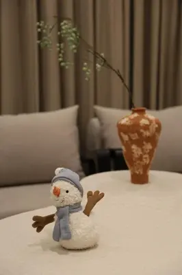 a small toy snowman on a table with a vase at \u6e29\u99a8\u53ef\u7231\u7684\u6574\u5957\u516c\u5bd3 in Dubai