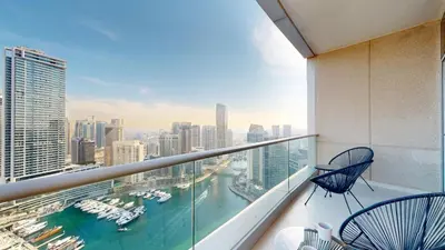a balcony with two chairs and a view of a harbor at Paloma - Three Bed with Mesmerizing Marina View in Dubai