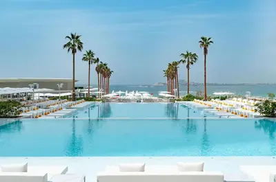 a large swimming pool with white chairs and palm trees at FIVE luxe JBR - High Floor Studio - Pool & Beach Access - Ventura Stays in Dubai
