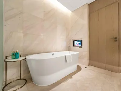 a white bath tub in a bathroom with marble walls at FIVE luxe JBR - High Floor Studio - Pool & Beach Access - Ventura Stays in Dubai