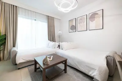 a hotel room with two beds and a table at Fresh New 2 Bedroom! Amazing Burj Khalifa View! 5-star Pool & Gym Access! in Dubai