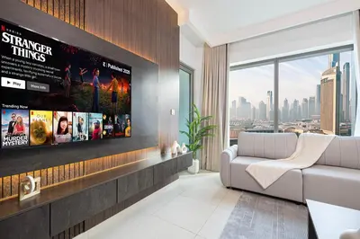 a living room with a large tv on a wall at Fresh New 2 Bedroom! Amazing Burj Khalifa View! 5-star Pool & Gym Access! in Dubai