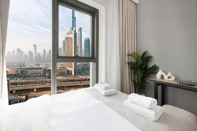a white bedroom with a view of a city at Fresh New 2 Bedroom! Amazing Burj Khalifa View! 5-star Pool & Gym Access! in Dubai