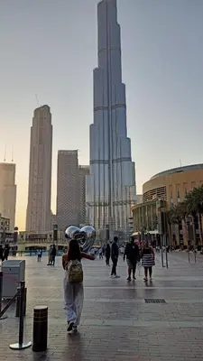 a group of people walking in a city with a tall building at 5 minutes walk to Dubai mall and Burj Khalifa in Dubai