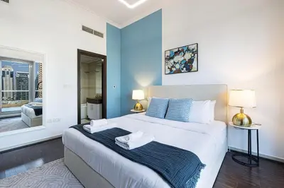 a bedroom with a large bed with blue walls at Panoramic Marina View - 1BR - Walk to the beach in Dubai