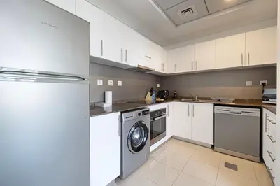 a kitchen with white cabinets and a washer and dryer at Panoramic Marina View - 1BR - Walk to the beach in Dubai