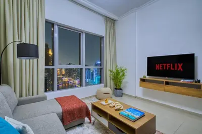 a living room with a couch and a tv at Waterfront 1BR - Marina Views - Walk to Beach & Mall in Dubai