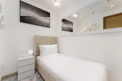 a white bedroom with a bed and a mirror at Daniels 1BR at Waves Grande In Sobha Hartland in Dubai