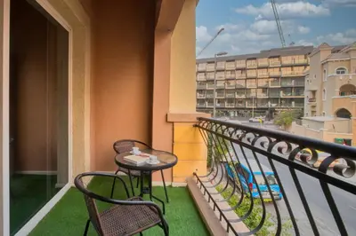 a balcony with two chairs and a table on a balcony at Spacious 1-BR Opposite Mall with Huge Pool & Gym in Dubai