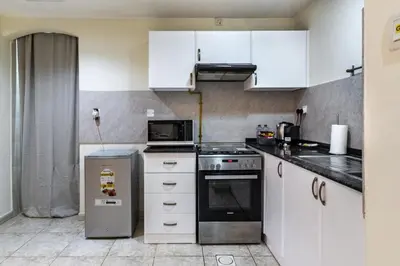 a kitchen with white cabinets and a stove top oven at Spacious 1-BR Opposite Mall with Huge Pool & Gym in Dubai