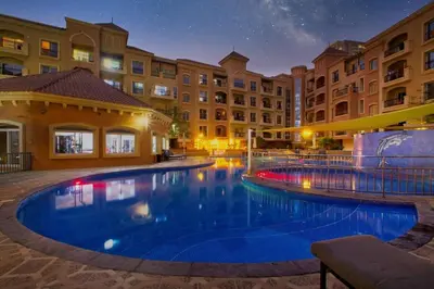 a large swimming pool in a hotel at night at Spacious 1-BR Opposite Mall with Huge Pool & Gym in Dubai