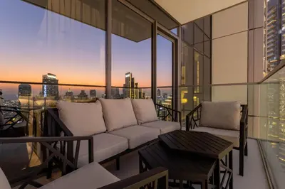 a living room with a couch and a table on a balcony at Brand New LUXE Downtown Dubai 46th Floor in Dubai