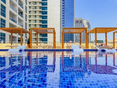 a swimming pool with chairs and tables and buildings at Stylish Studio with Stunning Marina Canal Views near to the Beach in Dubai