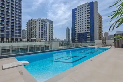 a large swimming pool on top of a building with tall buildings at Vogue JVC Binghatti Galaxy near Circle Mall, Studio Apartment with Balcony and City View, Access to all Amenities in Dubai