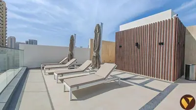 a row of chaise lounge chairs on the roof of a building at Vogue JVC Binghatti Galaxy near Circle Mall, Studio Apartment with Balcony and City View, Access to all Amenities in Dubai