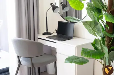 a desk with a laptop and a chair and a plant at Vogue JVC Binghatti Galaxy near Circle Mall, Studio Apartment with Balcony and City View, Access to all Amenities in Dubai