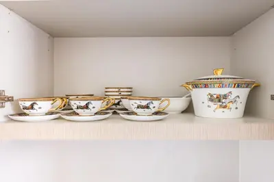 a row of cups and saucers on a shelf at Hermes-Style 2BR, Full Burj Khalifa View - Infinity Pool - Full Fountain View in Dubai