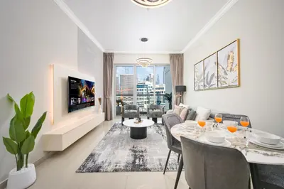 a living room with a table and chairs and a tv at 1BR Stunning Canal & Burj view, Luxury Stay at Fairview Residency in Dubai
