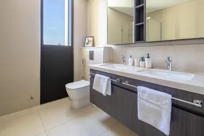 a bathroom with a toilet and a sink and a mirror at Frank Porter - Downtown Views in Dubai