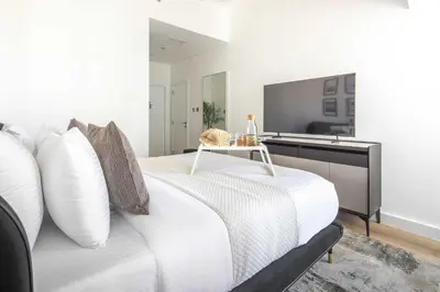 a bedroom with a white bed and a television at Frank Porter - Cayan Tower in Dubai