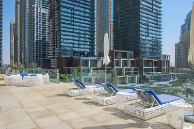 a row of chairs sitting on a patio with tall buildings at Frank Porter - Cayan Tower in Dubai