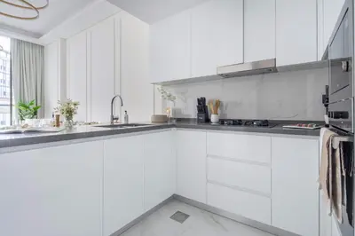 a white kitchen with white cabinets and a sink at Frank Porter - Samana Park Views in Dubai