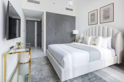 a white bedroom with a large bed and a television at Frank Porter - Samana Park Views in Dubai