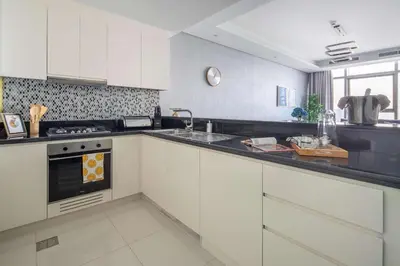 a kitchen with white cabinets and a sink at Frank Porter - Paramount Midtown in Dubai
