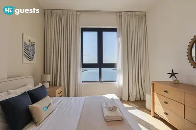 a bedroom with a large bed and a window at HiGuests - Elegant 1BR Retreat with Sea View in La Rive in Dubai