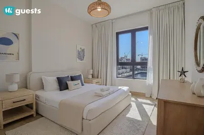 a white bedroom with a large bed and a window at HiGuests - Elegant 1BR Retreat with Sea View in La Rive in Dubai