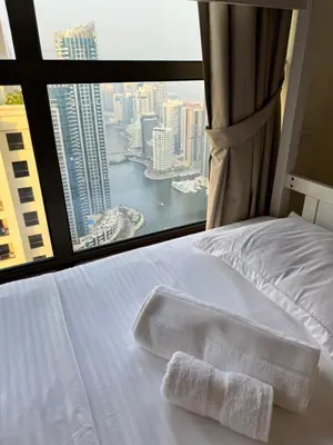 a bed with a towel on it in front of a window at Best view homes in Dubai